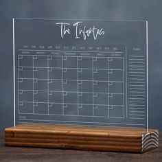 a clear desk calendar on a wooden stand with the word'the inquisita'written across it