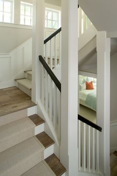 there is a bed and stairs in this house with white walls, wood floors, and carpeted flooring