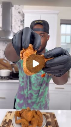 a man in black gloves is holding up a piece of fried food to the camera