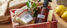 a red basket filled with personal care items on top of a wooden table next to lemons