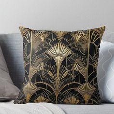 a black and gold art deco design throw pillow on a gray couch with white pillows