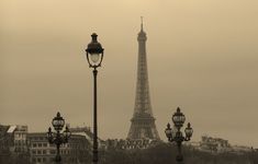 the eiffel tower towering over the city of paris in sepia - toned photograph