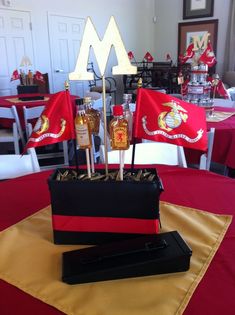 a table topped with a black box and red cloth covered tablecloth next to two flags