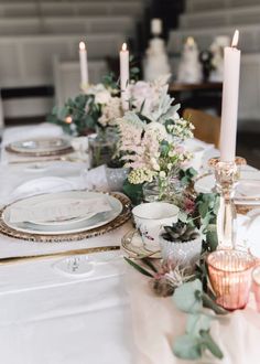 the table is set with candles and plates