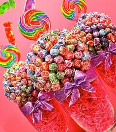 the colorful lollipops are on display in front of a pink background with purple bows