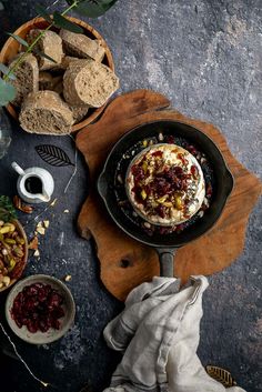 an iron skillet filled with food on top of a wooden cutting board next to other dishes