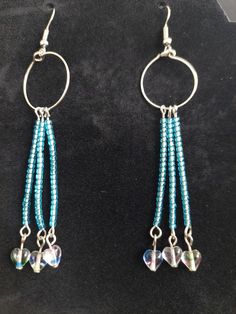 the earrings are made with glass beads and silver hoop earwires on a black velvet surface