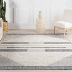 a living room area with a rug, chair and potted plant