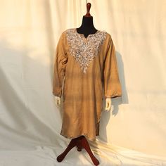 Discover the epitome of elegance with our Plain Beige Brown Base Color Kurti Shirt, adorned with exquisite machine embroidery. The detailed patterns around the shoulders and neck create a charming contrast to the solid beige outfit, featuring stunning embroidery. Made from high-quality, soft pashmina, this top ensures comfort and style for the summer and spring seasons. Its detailed embroidery and graceful patterns make it a perfect choice for semi-formal and formal events. Embrace versatility with this article, pairing it effortlessly with simple jewelry and statement shoes for various occasions. Ideal for both indoor and outdoor use, each uniquely crafted piece is available in limited quantity and sizing, ensuring you stand out with exclusivity and finesse. Product specifications: Base c Semi-stitched Long Sleeve Kaftan With Dabka Work, Semi-stitched Long Sleeve Kaftan For Festivals, Long Sleeve Semi-stitched Kaftan With Dabka Work, Festival Semi-stitched Long Sleeve Kaftan, Festive Long Sleeve Kaftan With Dabka Work, Festive Resham Embroidered Tunic Top, Festive Long Sleeve Kaftan With Resham Embroidery, Long Sleeve Resham Embroidered Kaftan For Eid, Traditional Long Sleeve Embroidered Dress