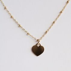 Reflect your deep affection for your loved ones with Hailey Necklace, a stunning necklace that has an artistically crafted Heart-shaped charm attached to a sparkling chain. Hailey Necklace is handcrafted from high-quality Goldfilled material that not only gives it an extra layer of sparkle but also provides durability and sturdiness. With its charming Heart-shaped charm along with a simplistic yet elegant Goldfilled chain, Hailey Necklace will serve as a perfect gift for your loved ones on speci Valentine's Day Yellow Gold Heart Charm Necklace, Heart-shaped Gold Locket Necklace With Adjustable Chain, Valentine's Day Gold-plated Heart Charm Necklace, 14k Yellow Gold-filled Heart Necklace For Valentine's Day, Heart-shaped 14k Gold Charm Necklace For Valentine's Day, Stunning Necklace, Loved Ones, Chain Lengths, Gold Filled