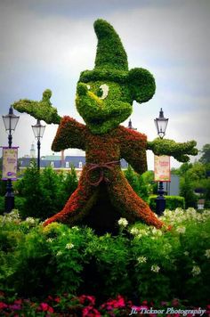 the topiary statue is made to look like a wizard's hat and holding his hands out