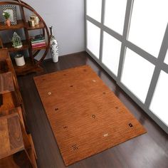 a brown rug is on the floor in front of a book shelf and windows with glass panes