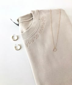 a sweater, earrings and t - shirt on a white surface with the word peace comes written in gold