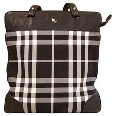 A Burberry tote/shoulder bag made of black & white canvas with the Burberry tartan pattern. The bag features black leather trim and silver toned hardware. The interior is lined with a purple canvas and next to the major compartment it features three side pockets of which one has a zipper. The bag will be delivered with its Burberry dust bag and the authenticity card. The condition of the bag is very good, with hardly any signs of use. Measurements Width:39 cm Height:42 cm Shoulder handle drop: 22 cm. Burberry Tartan, Black White Canvas, Burberry Tote, Purple Canvas, Black And White Canvas, Tartan Pattern, White Canvas, Leather Trim, Fashion Handbags