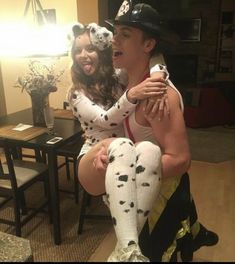 a man and woman dressed up in costumes sitting on a table with their legs wrapped around each other