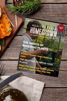 a magazine sitting on top of a wooden table next to a plate of food and utensils