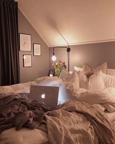 an apple laptop sitting on top of a bed in a room with pictures above it