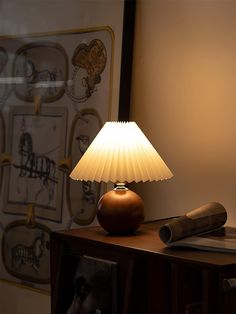 a lamp sitting on top of a wooden table next to a wall with pictures behind it