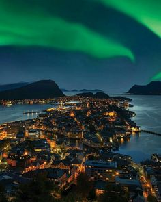 an aerial view of the city lights and aurora bores in the sky over water