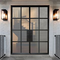 a white brick building with black iron railings and two lights on each side of the door