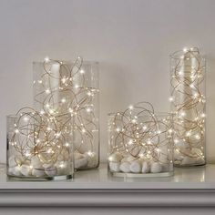 three glass vases filled with white balls and lights