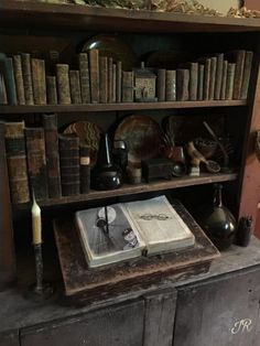 an old wooden book shelf filled with books and other antique items on top of it