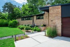 a brick house with green grass and trees in the background