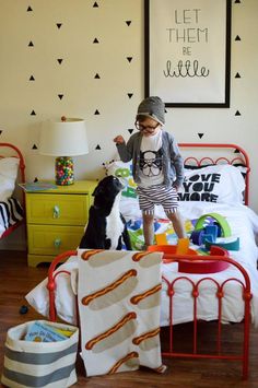 a little boy standing on top of a bed next to a black and white dog