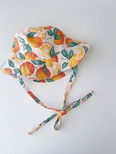 "Handmade brimmed orange print with soft pink background sun hat Breathable 100% cotton fabric Cotton lining | satin lining Measurements: Tie length for all - 16\" / 30-31 cm 0-3 months - 13\" / 33cm 3-6 months - 15\" / 38 cm 6-12 months - 17\" / 43cm 12-24 months - 18.5\" / 46-48 cm 2-4 years - 20\" / 50 cm 4-7 years - 20.5\" / 52 cm 7-12 years - 21.5\" / 54 cm Adult Small - 22\"/56 cm Adult Medium - 23\"/58 cm Adult Large - 24\"/60 cm Care instructions: Machine wash in cold water, gentle dry, Adjustable Orange Sun Hat For Vacation, Orange Summer Sun Hat For Vacation, Adjustable Orange Sun Hat For Summer, Orange Brimmed Sun Hat For Vacation, Orange Brimmed Sun Hat For Summer, Orange Sun Hat For Summer, Adjustable Summer Sun Hat In Orange, Summer Orange Adjustable Sun Hat, Adjustable Orange Summer Sun Hat