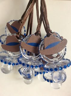 three clear glass ornaments with blue beads and twine around the strings on a white surface