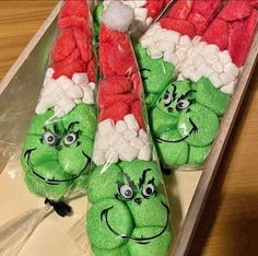 some very cute green and red items in a plastic container with santa hats on them