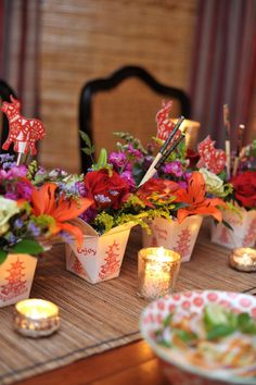 there are many small cups with flowers in them on the table next to some candles