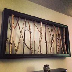 there is a painting on the wall with some branches in front of it and another piece of artwork behind it