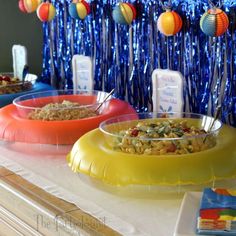 three bowls filled with food sitting on top of a counter next to balloons and streamers