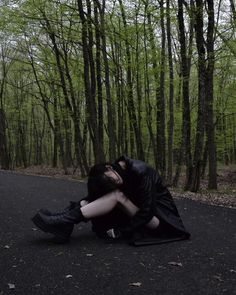 a woman sitting on the ground in front of trees