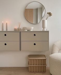 a white room with two drawers and a mirror on the wall next to a chair