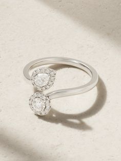 two diamond rings sitting on top of a white surface with shadows coming in from the background