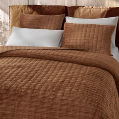 a bed with brown bedspread and white pillows