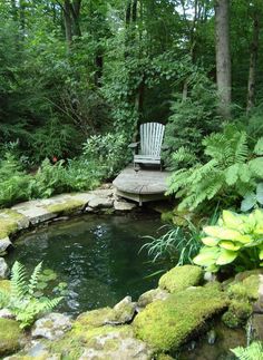 a chair sitting on top of a wooden bench next to a small pond filled with water