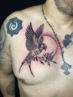 a man's chest with a bird and rose tattoo on it