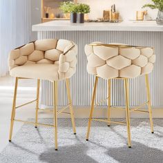 two stools in the middle of a kitchen with white counter tops and walls behind them