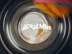 the word jacquemus written in white ink on a metal object with a blurry background