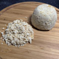 a wooden cutting board topped with a ball of bread and a pile of crumbs