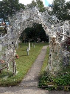 an archway decorated with spider webs and skeletons in a cemetery yard for halloween decorations