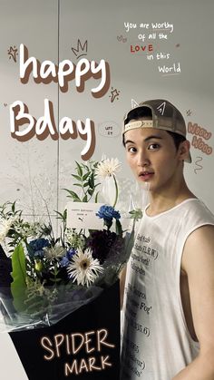 a young man holding a bouquet of flowers in front of a sign that says happy bday