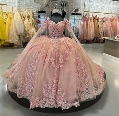 a pink ball gown is on display in a store, with other dresses behind it