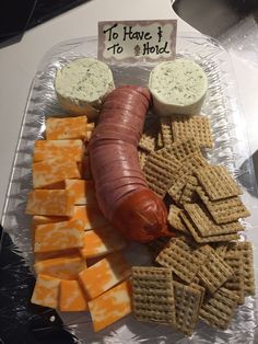 a hot dog, crackers and cheese on a plastic tray