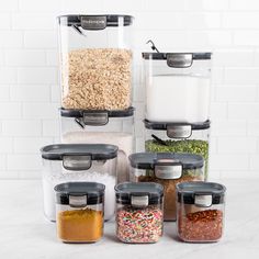 an assortment of food in containers on a white counter top, including cereal and sprinkles