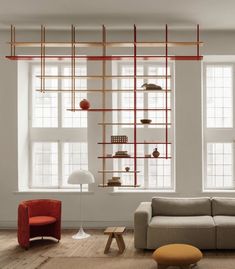 a living room filled with lots of furniture next to two large windows and bookshelves