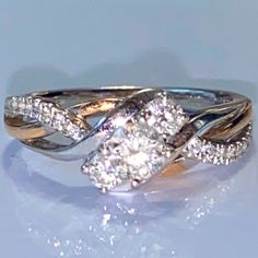 two tone gold and white diamond ring with twisted shans on the sides, set against a light blue background